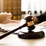Judge's Gavel Sits on Lawyer's Desk As They Discuss With Client