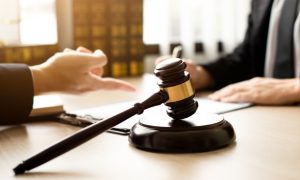 Judge's Gavel Sits on Lawyer's Desk As They Discuss With Client