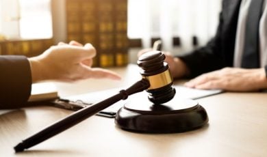 Judge's Gavel Sits on Lawyer's Desk As They Discuss With Client
