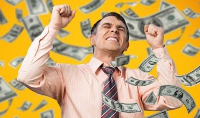 Cash Flies Around Excited Man With Fisted Hands Wearing Pink Button Down Shirt and Tie
