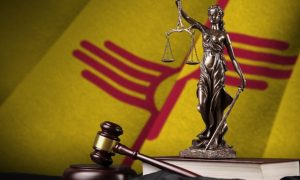 Yellow and Red State Flag of New Mexico, Background to Metal Statue of Lady Justice Sitting on Book
