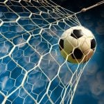 Blue and White Skies Background to Close Up Image of Soccer Ball Hitting Back of Net