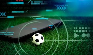 Green Grass with Mini Soccer Ball and Black Cell Phone in Sports Betting Concept