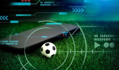 Green Grass with Mini Soccer Ball and Black Cell Phone in Sports Betting Concept