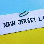 Yellow File with New Jersey Law in Black Ink Sits on Blue Desk