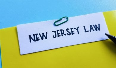 Yellow File with New Jersey Law in Black Ink Sits on Blue Desk
