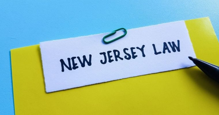 Yellow File with New Jersey Law in Black Ink Sits on Blue Desk
