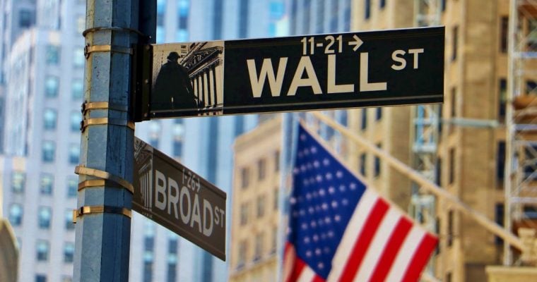 NYC Buildings and American Flag Hangs in the Background of Wall Street Sign