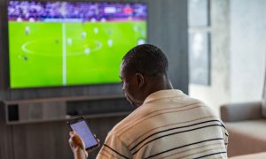 Man Uses Mobile Phone for In-Game Sports Betting In Living Room
