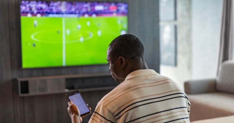 Man Uses Mobile Phone for In-Game Sports Betting In Living Room