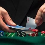 Cards Dealer Pulls Out Ace from Deck of Playing Cards with Stacks of Poker Chips on Table