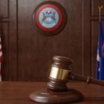 Judge's Gavel Sits on Wooden Desk Inside Courtroom with Michigan & US Flag Background