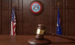 Judge's Gavel Sits on Wooden Desk Inside Courtroom with Michigan & US Flag Background
