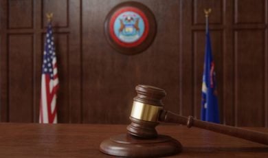 Judge's Gavel Sits on Wooden Desk Inside Courtroom with Michigan & US Flag Background