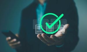 Man Holding Cell Phone in One Hand And the Other Palm Faces Up with Green Check Mark Hovering Above