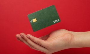 Cupped Hand with Green Visa Card Hovering Above it on Red Background
