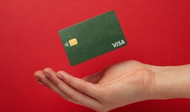 Cupped Hand with Green Visa Card Hovering Above it on Red Background