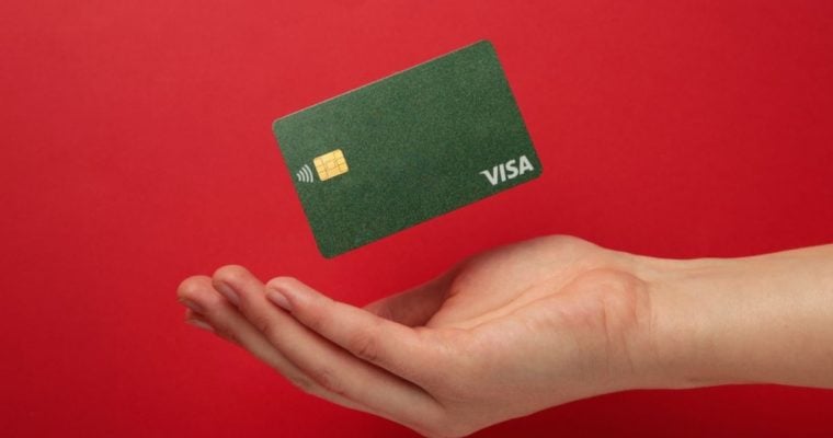 Cupped Hand with Green Visa Card Hovering Above it on Red Background