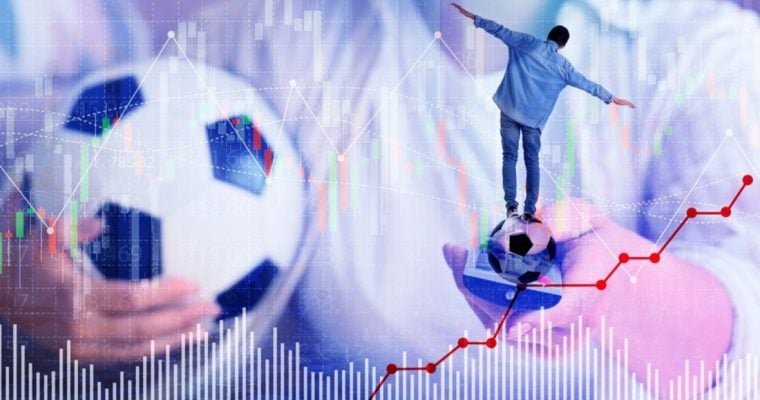 Man Holds Soccer Ball in One Hand and TV Remote In Another With Smaller Man Balancing and Graphs Below