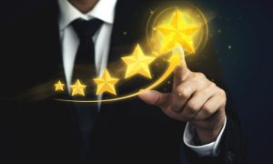 Man in Black Suit and Tie Points to Biggest Gold Star out of 5