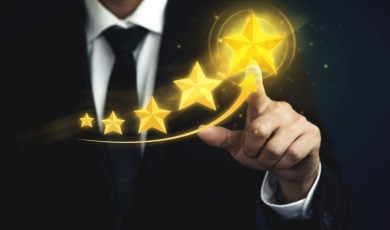 Man in Black Suit and Tie Points to Biggest Gold Star out of 5