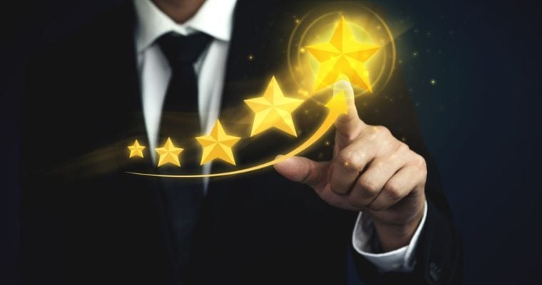 Man in Black Suit and Tie Points to Biggest Gold Star out of 5