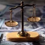 $100 Bills Layed Out on Table with Brass Scales Sitting on Top
