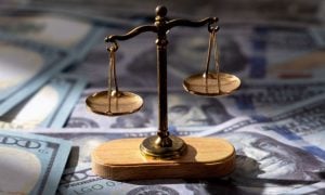 $100 Bills Layed Out on Table with Brass Scales Sitting on Top