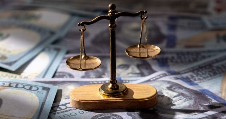 $100 Bills Layed Out on Table with Brass Scales Sitting on Top