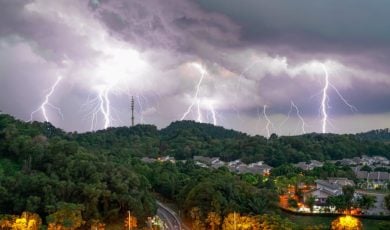 Huge Thunderstorm with Many Lightning Strikes Hit Green Hills Above Town Tucked Inside