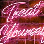 Hot Pink Neon Sign Hanging on Red Brick Wall Reads Treat Yourself