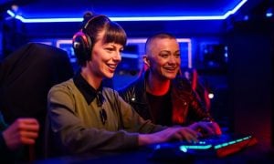 Neon Blue Lights Inside Game Room Behind Two Women Playing PC Game