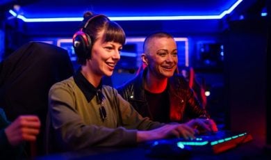 Neon Blue Lights Inside Game Room Behind Two Women Playing PC Game