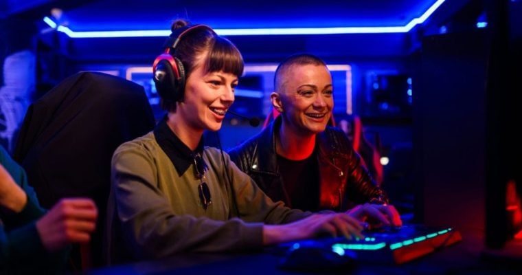 Neon Blue Lights Inside Game Room Behind Two Women Playing PC Game