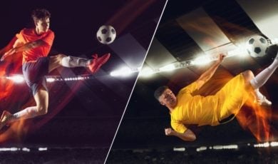 Two Young Male Soccer Players Mid-Air Kicking Ball Inside Stadium