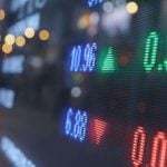 Blue, Green and Red Numbers Displayed on a Stock Board on Trading Floor
