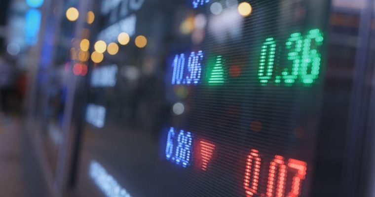 Blue, Green and Red Numbers Displayed on a Stock Board on Trading Floor