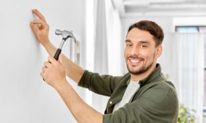 a man hammering a nail into a wall