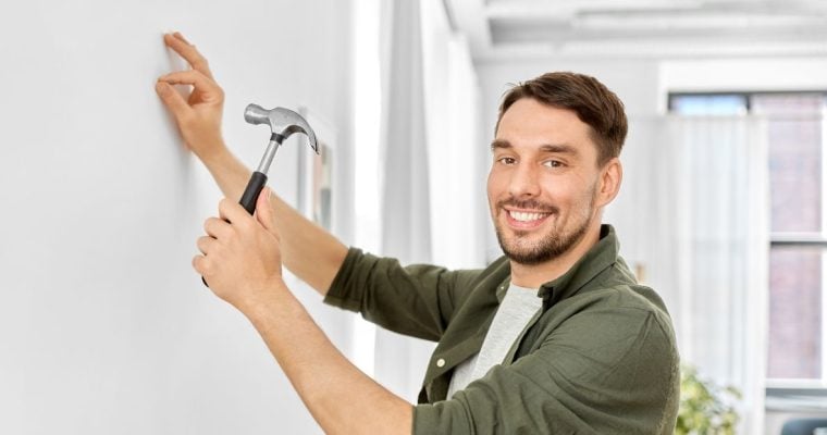 a man hammering a nail into a wall