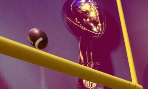 A view of the Super Bowl trophy and an NFL football nearing the goal post