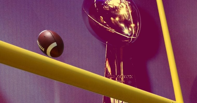 A view of the Super Bowl trophy and an NFL football nearing the goal post