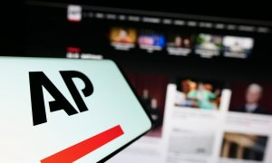Cellphone with logo of US news agency Associated Press (AP) on screen in front of website. Focus on center-left of phone display