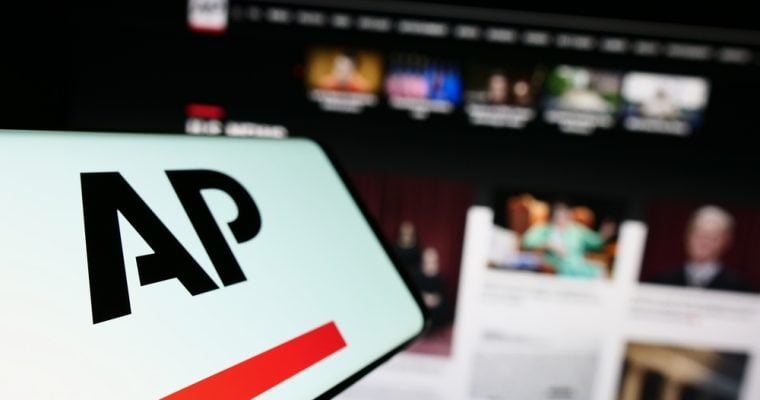 Cellphone with logo of US news agency Associated Press (AP) on screen in front of website. Focus on center-left of phone display