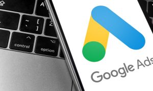 a mobile phone with google ads app on it sitting on a laptop computer