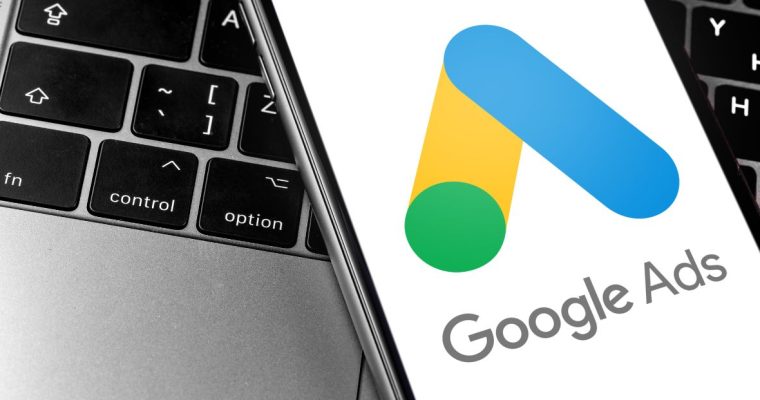 a mobile phone with google ads app on it sitting on a laptop computer