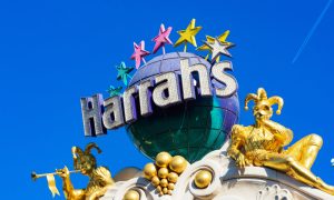 Two gilded jester, joker sculptures blow trumpets seating between globe and stars, and on outdoor marquee of Harrah's casino and hotel