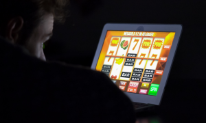 A person plays a casino slot game in the dark