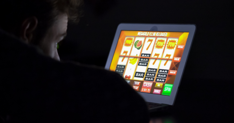 A person plays a casino slot game in the dark
