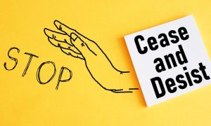 an illustration of a hand with stop by it next to a cease and desist sign