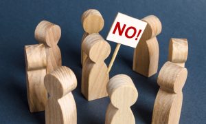 a series of wooden people in a circle with one in the middle holding a no sign